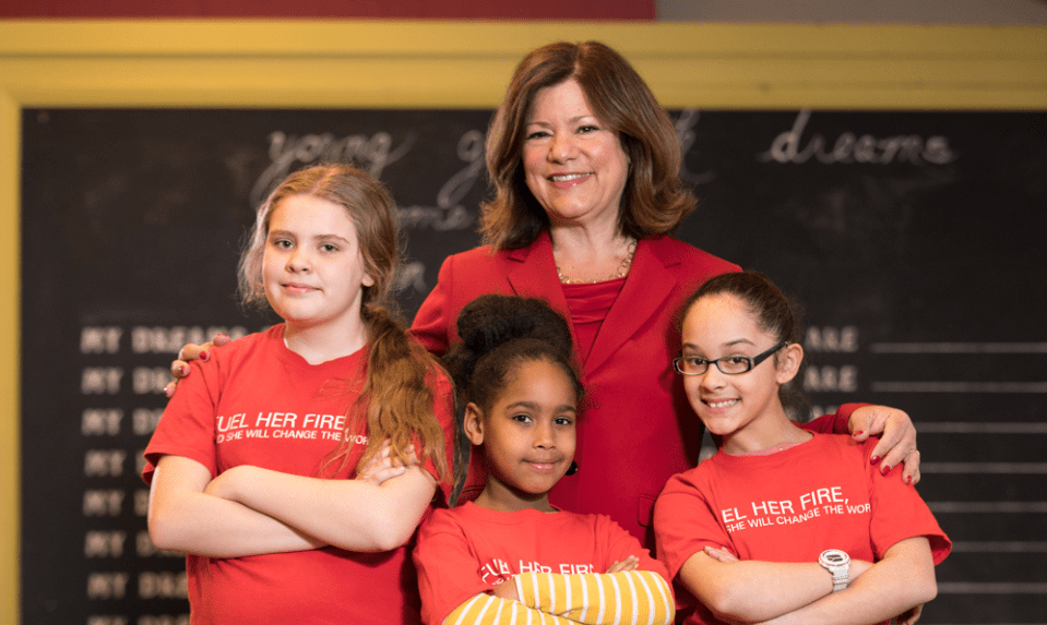 CEO standing with three girls in red shirts