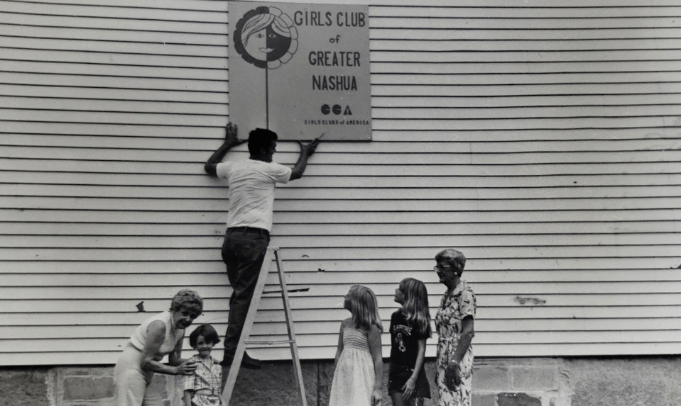man hanging up girls club sign