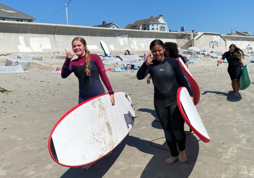 two girls holding surfboards at the beach