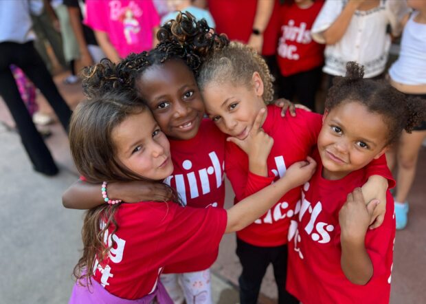 four girls red t-shirts embracing
